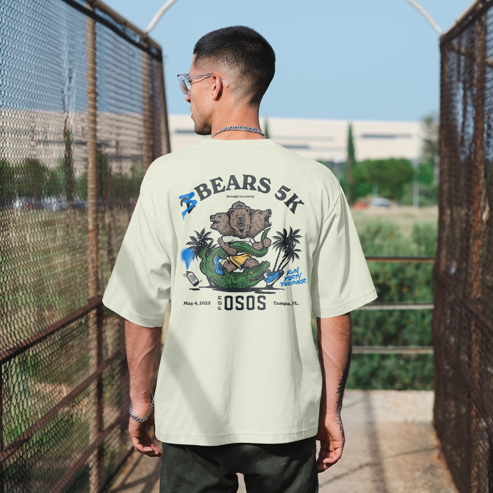 A man seen from behind in a 2 Bears 5K t-shirt: the two-headed bear riding an alligator, Tampa, May 4 2025.